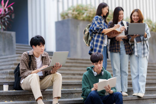 istock Group Of Young Asian Students Collaborating Outdoors at University. Teamwork and Knowledge Sharing. Asian Students Engaged in Collaborative Learning Outdoors. 1551209616