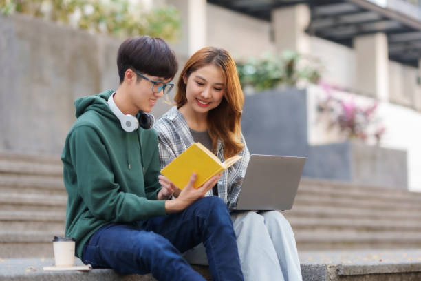 istock Happy Two Young Asian Students Collaborating Outdoors at University. Teamwork and Knowledge Sharing. Asian Students Engaged in Collaborative Learning Outdoors. 1551209640