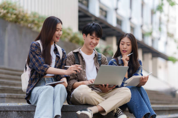 istock Group Of Young Asian Students Collaborating Outdoors at University. Teamwork and Knowledge Sharing. Asian Students Engaged in Collaborative Learning Outdoors. 1551209665