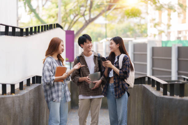 istock Group Of Young Asian Students Collaborating Outdoors at University. Teamwork and Knowledge Sharing. Asian Students Engaged in Collaborative Learning Outdoors. 1551209689