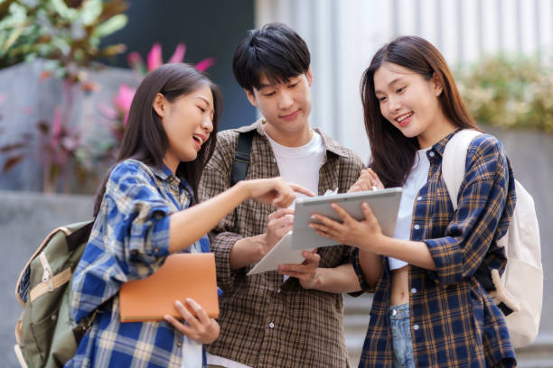 istock Group Of Young Asian Students Collaborating Outdoors at University. Teamwork and Knowledge Sharing. Asian Students Engaged in Collaborative Learning Outdoors. 1551209706