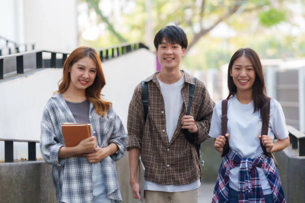 istock Group Of Young Asian Students Collaborating Outdoors at University. Teamwork and Knowledge Sharing. Asian Students Engaged in Collaborative Learning Outdoors. 1551209719
