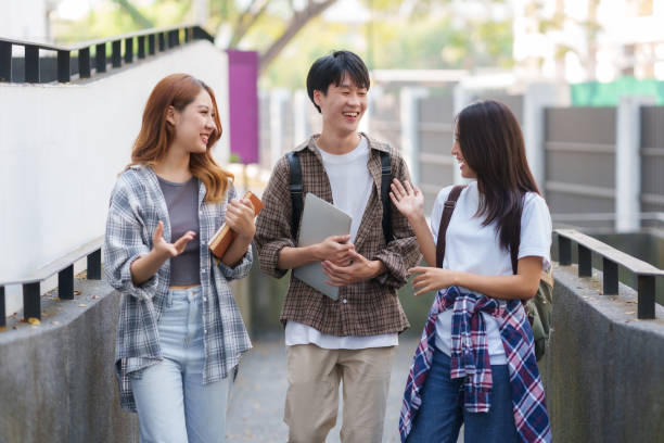istock Group Of Young Asian Students Collaborating Outdoors at University. Teamwork and Knowledge Sharing. Asian Students Engaged in Collaborative Learning Outdoors. 1551209738