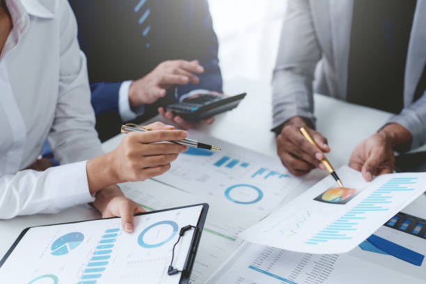 istock Group of business people working together on new project with planning analytical report at meeting. Businesspeople meeting together pointing to graph assess business profits. 1551209771