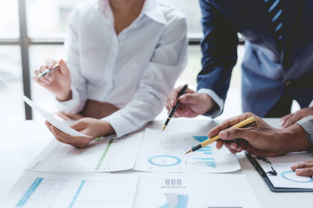 istock Group of business people working together on new project with planning analytical report at meeting. Businesspeople meeting together pointing to graph assess business profits. 1551209779