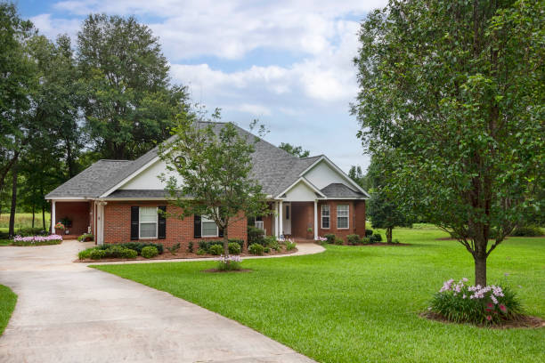 istock Traditional Brick House on Green Lawn with Mature Trees 1551209844