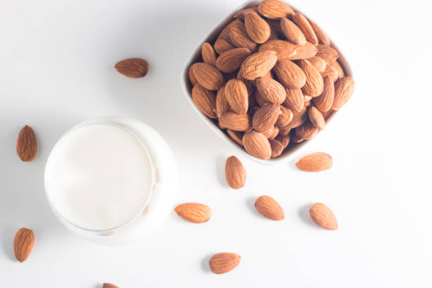 istock Organic almond milk in glass with raw almonds on white table 1551210275