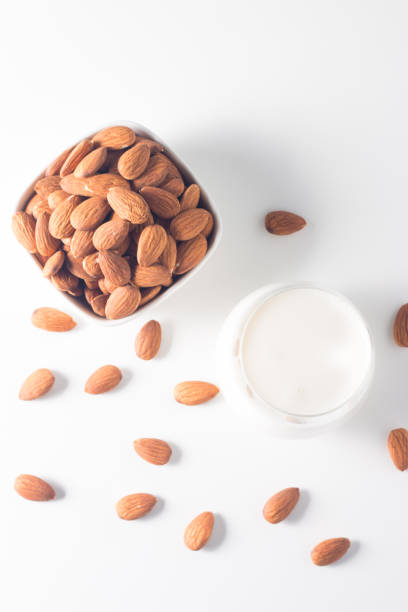 istock Organic almond milk in glass with raw almonds on white table 1551210323