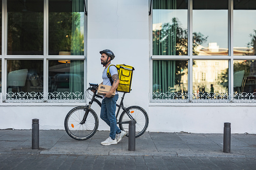 delivery man with his backpack riding a bicycle through the city with a package in his hand