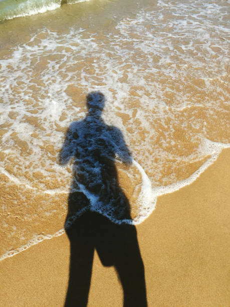 istock Man shadow on sand at beach and seaside 1551211493