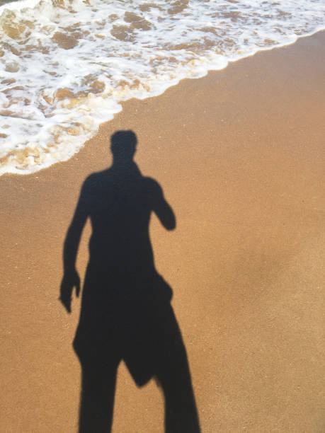 istock Man shadow on sand at beach and seaside 1551211518