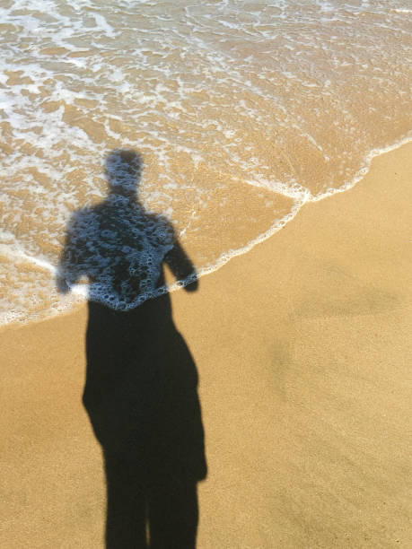 istock Man shadow on sand at beach and seaside 1551211535