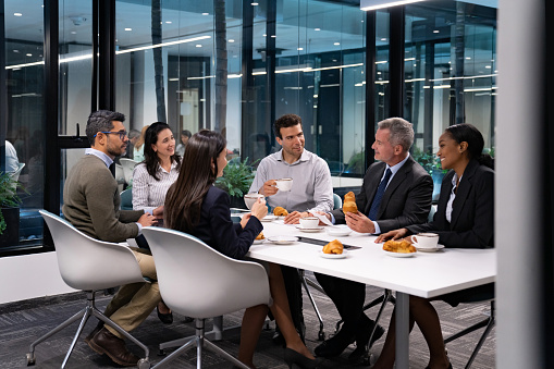 istock Group of business people in a meeting eating breakfast 1551218340