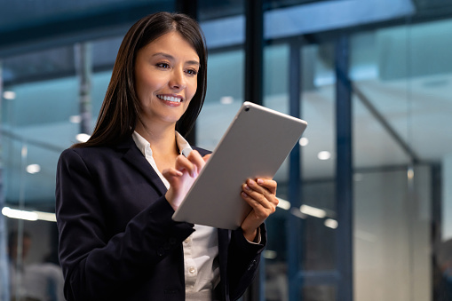 Portrait of a successful Latin American business woman working at the office using a tablet