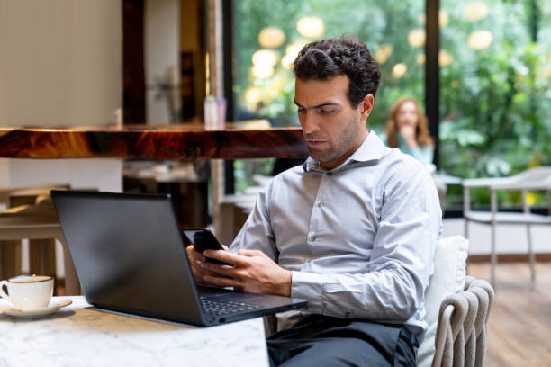 istock Business man working on his laptop at a cafe and sending a text message 1551219349