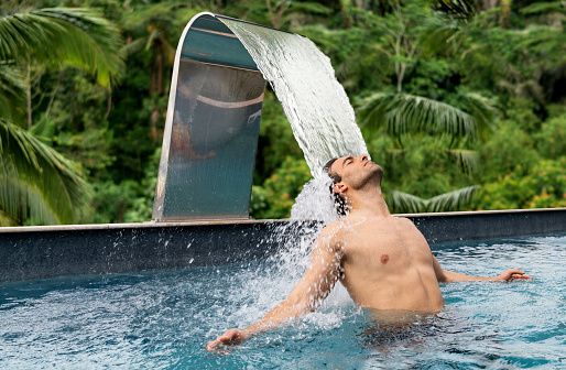 Handsome Latin American man relaxing in a massage pool at the spa  - luxury concepts