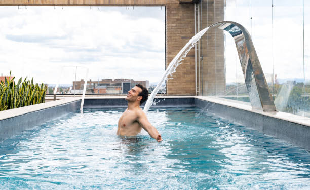 Happy Latin American man in the pool at the spa getting a back massage - luxury hotel concepts