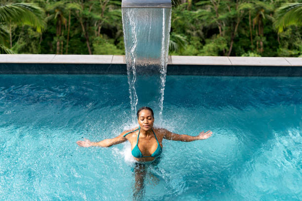 istock Beautiful woman in the pool at the spa getting a back massage 1551219420