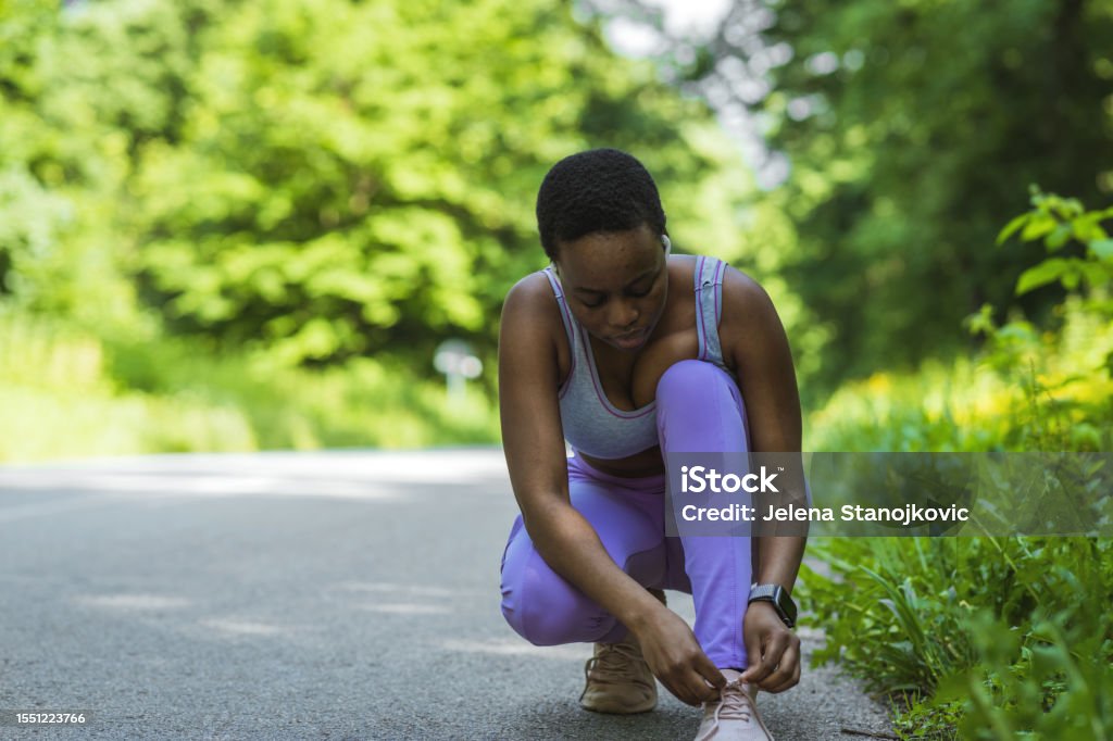 Shot of a sporty young woman tying her shoelaces before her run. 20-24 Years Stock Photo