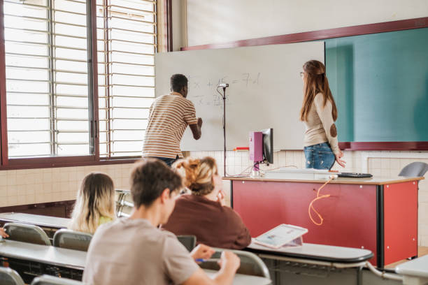 istock A student solves a task on the blackboard in front of the teacher and his university classmate 1551230648