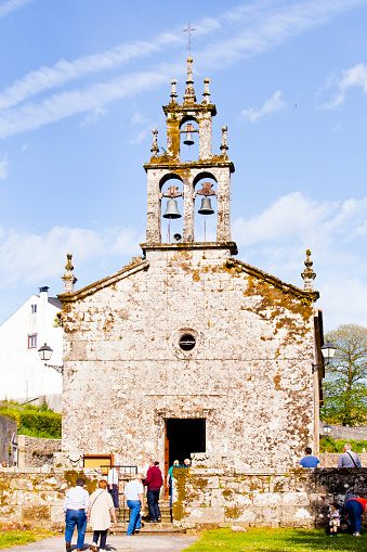 San Pedro da Porta church facade and cattail, Sobrado, A Coruña, Galicia, Spain. Located at the entrance of Sobrado dos monxes monastery. Camino de Santiago. Rear view of incidental people coming in.