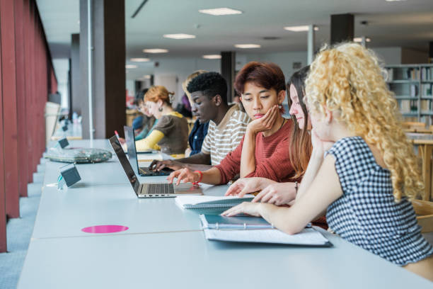 istock Group of students from different cultures and backgrounds studying together in the library 1551242881