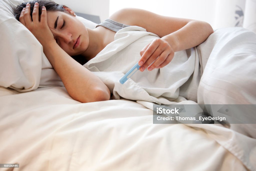 Donna controllando la temperatura a letto - Foto stock royalty-free di Febbre