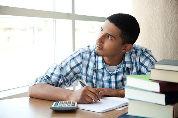 Latin student looking out the window while studying math stock photo