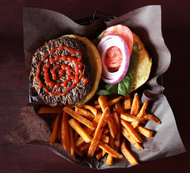 top view of plate with burger and sweet potato fries on rustic wooden table
