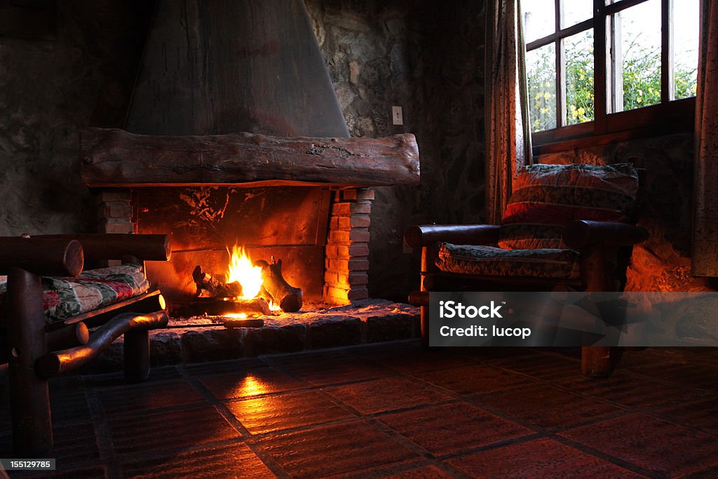 Fireplace with wooden logs, chairs and window  Fireplace Stock Photo