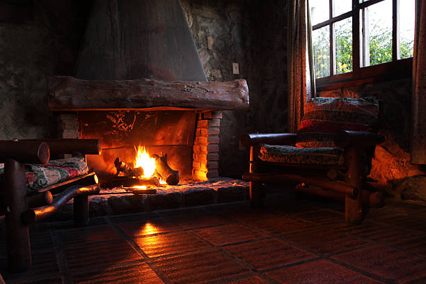 Fireplace with wooden logs, chairs and window stock photo