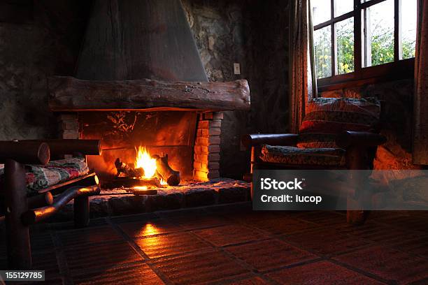 Fireplace With Wooden Logs Chairs And Window Stock Photo - Download Image Now - Fireplace, Log Cabin, Cozy