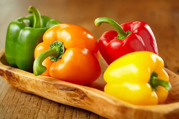 Photo of Various colorful bell peppers in wooden basket