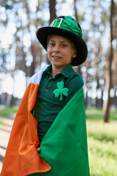 menino branco alegre coberto com bandeira irlandesa. retrato de uma criança feliz celebrando o dia de são patrício no dia 7 de março - republic of ireland flag human face irish culture - fotografias e filmes do acervo