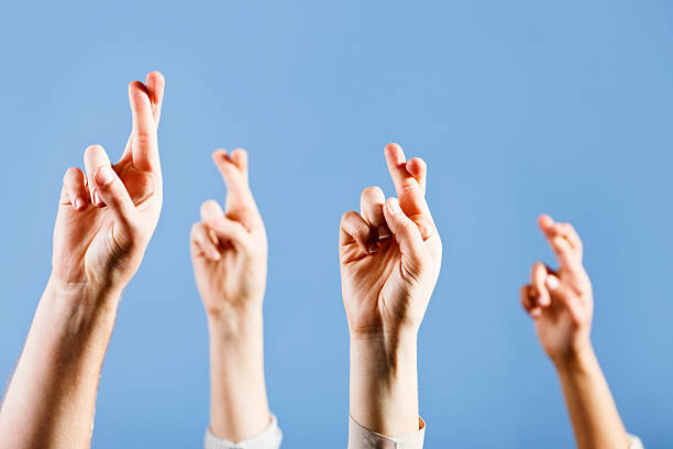 istock Four superstitious hopeful crossed fingers against blue background 155131124