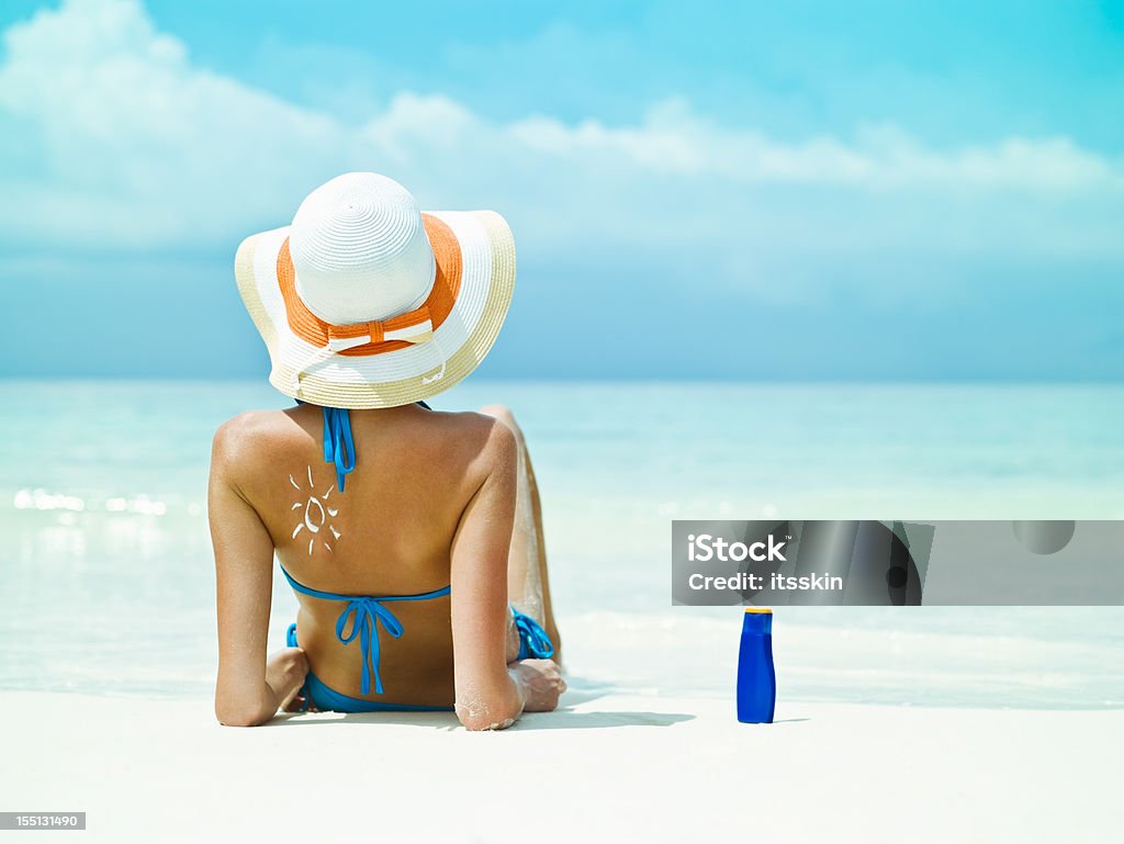 Сидит рядом с океаном с Солнцезащитный крем для бутылок - Стоковые фото Солнцезащитный крем роялти-фри