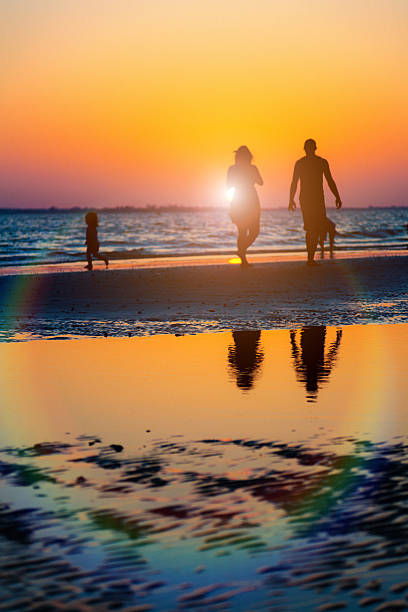 família caminhadas na praia ao pôr-do-sol - silhouette three people beach horizon - fotografias e filmes do acervo