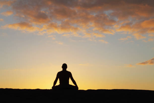 istock silhouette of a meditating man against sunset sky 155132338