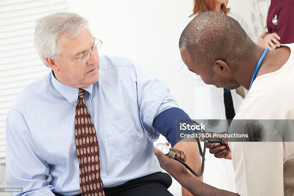 Médical professionnel en prenant la tension artérielle de l'homme au bureau du médecin - Photo de Docteur libre de droits