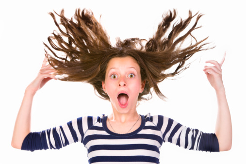 Surprised and awe teenage girl with flying hair. Strong motion blur in hands and hair.