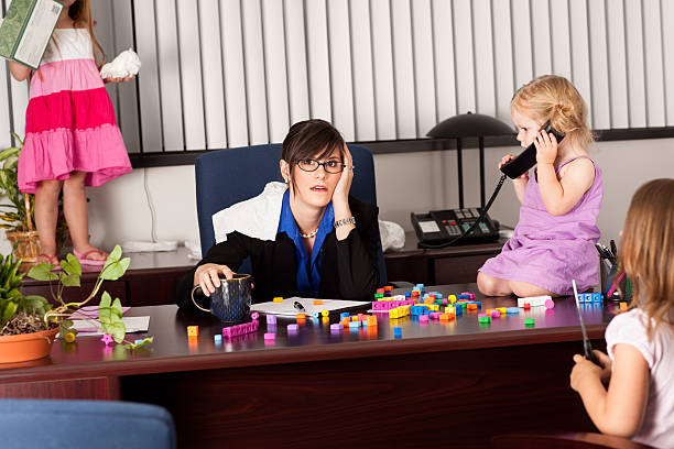 Stressed Business Woman Working with Children in Office Color image of a young business woman stressed out in her office because of her children being there and causing chaos. school receptionist stock pictures, royalty-free photos & images