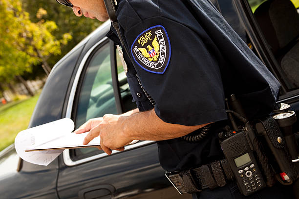 istock Policeman with clipboard beside police vehicle 155134338