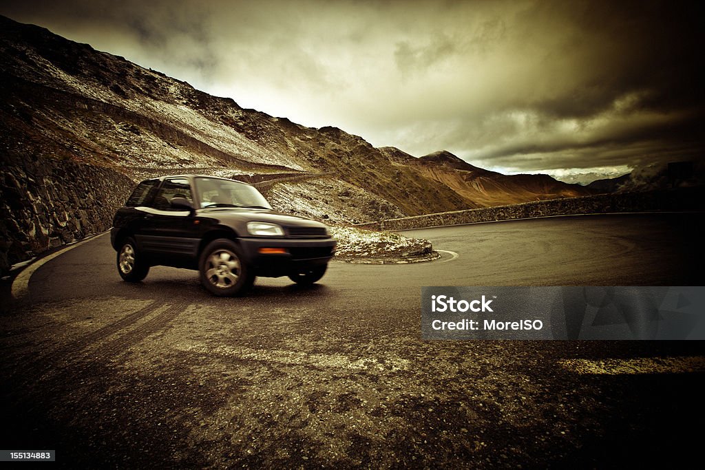 Automóvil por una ruta de montaña, cielo dramático, hora de viaje - Foto de stock de Coche libre de derechos