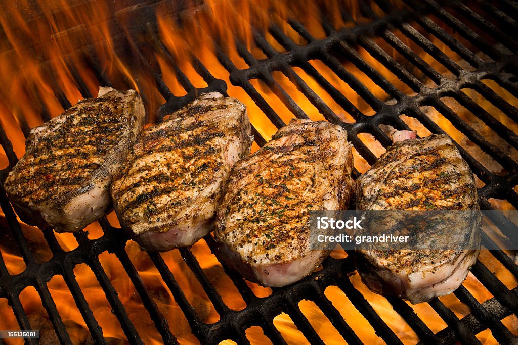 Chuletas de cerdo a la parrilla en fuego - Foto de stock de Asar a la parrilla libre de derechos