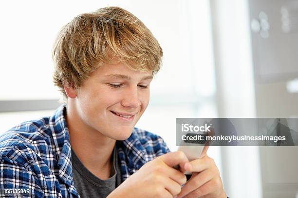 Foto de Garoto Adolescente Com Telefone Em Classe e mais fotos de stock de 16-17 Anos - 16-17 Anos, Adolescente, Comunicação