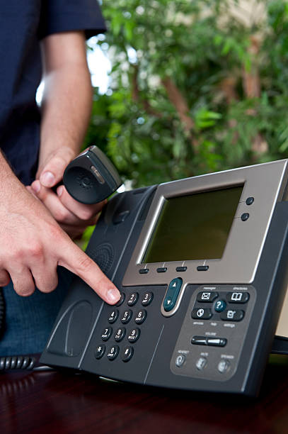 istock Holding an office telephone and dialing a number 155135884