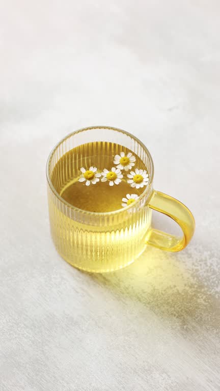 A cup of Chamomile tea on light wooden table with flowers