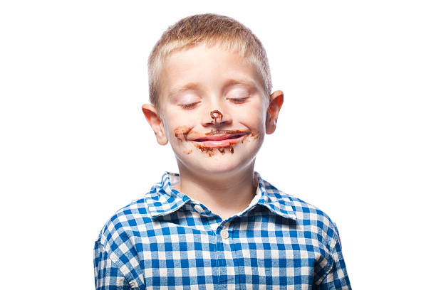 A young girl nerd is eating a chocolate bar and the sugar has gone to her head. She has smeared chocolate all over her face and doesn't know what to do with herself as she loves chocolate so much.