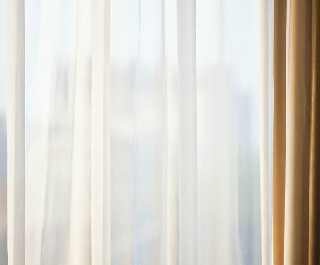 Simple background looking through hotel room curtains, with defocussed buildings in the background.