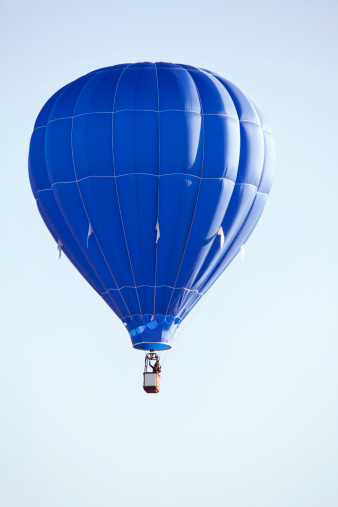 Goreme, Turkey - April 12, 2023: A picture of a green and white hot air balloon flying in a blue sky in Cappadocia.